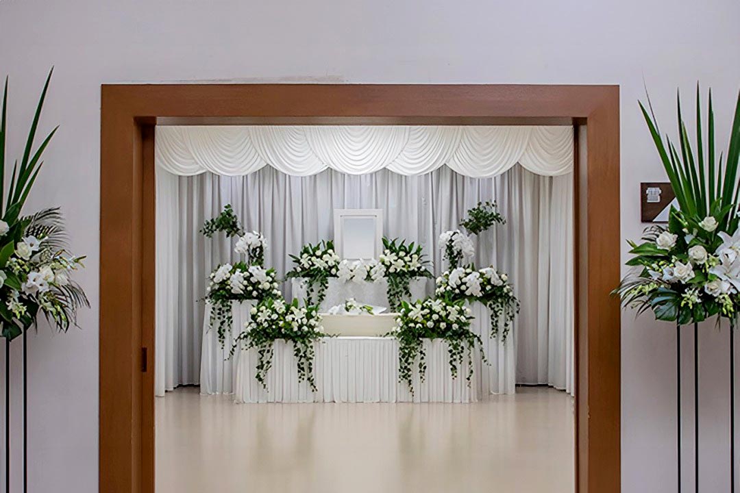 白を基調とした花で作られた祭壇があり、さらに入り口にもスタンドの花が飾られています