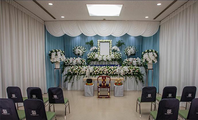 白を基調とした花で作られた祭壇があり、手前には参列者用のたくさんの椅子が並んでいます