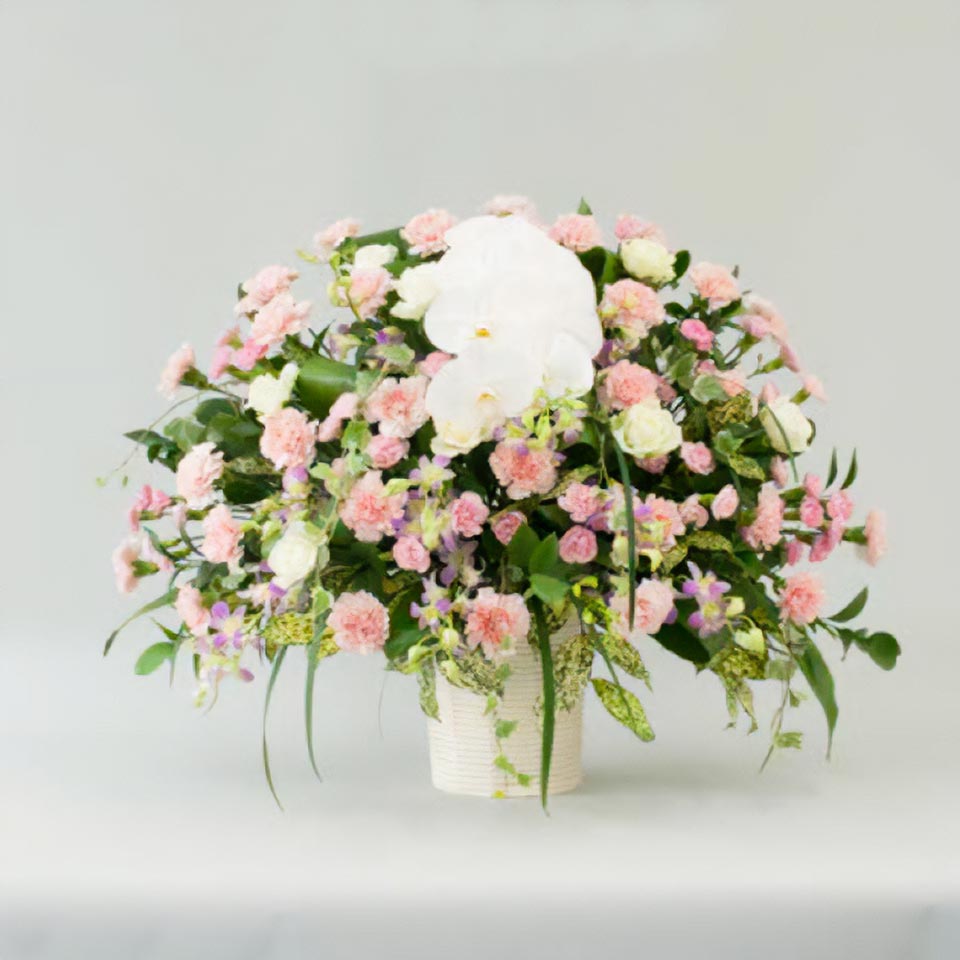 白やピンクなどの花と緑の葉で作られた家族花
