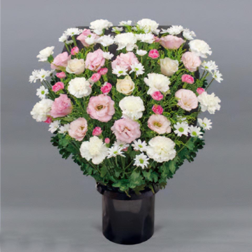 白やピンクなどの花と緑の葉で作られた追悼の供花